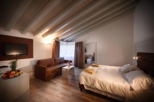 a bedroom with a bed and a couch and a television at Bella Hotel & Restaurant with private dock for mooring boats in San Felice del Benaco
