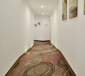 a hallway with a carpeted floor and paintings on the walls at Hotel Engelhorn in Leimen