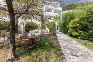 a park bench next to a tree and a building at Apartments Villa Mili in Brela