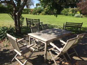 uma mesa de madeira com quatro cadeiras e uma árvore em Mill Farm em Milton Keynes