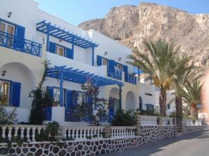 a blue and white building with palm trees and a mountain at Karidis Hotel in Kamari