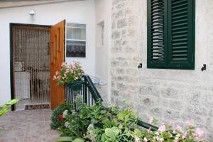 a door to a house with green shutters and flowers at Apartments Andrea in Šibenik