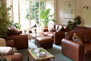 a living room with brown leather couches and tables at Flackley Ash Country House Hotel in Rye