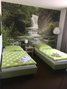 a bedroom with two beds and a waterfall mural at Adam Hotel in Giesen