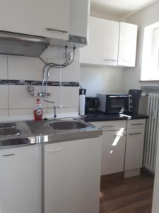 uma cozinha com armários brancos e um lavatório em Ferienwohnung Messmer em Constança