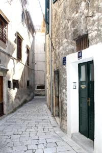 an alley in an old building with a green door at Apartments Andrea in Šibenik +15 photos