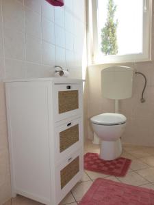 a white bathroom with a toilet and a window at Apartment Tena in Novalja +22 photos
