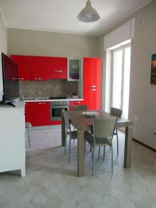 トラーニにあるLa Casa degli Artistiのキッチン(赤いキャビネット、木製テーブル、椅子付)