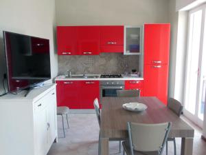 トラーニにあるLa Casa degli Artistiの赤いキャビネットとテレビ付きのテーブルが備わるキッチン