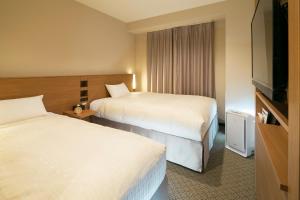 um quarto de hotel com duas camas e uma televisão de ecrã plano em JR-East Hotel Mets Kitakami em Kitakami