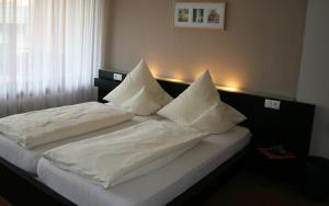 a bedroom with two beds with white sheets and pillows at Hotel-Restaurant Zur Post in Roßbach