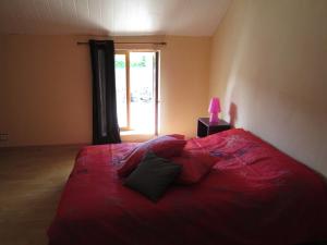 a red bed in a room with a window at La Ferme de la Petite Noé in Tracy-sur-Mer