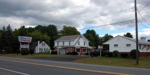 Une rue avec des maisons blanches et un panneau pour une pharmacie dans l'établissement Budgetel Inn Glens Falls-Lake George-Saratoga, à Glens Falls
