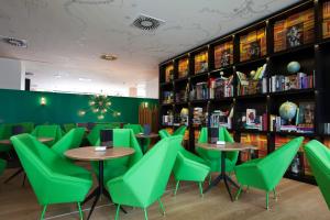a restaurant with green chairs and tables and bookshelves at Vincci Bit in Barcelona