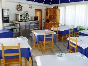 un restaurante con mesas blancas y sillas azules y una cocina en Hospedaje El Marinero en Isla