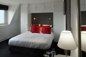 a bedroom with a large bed with red pillows at Beach Hotel in De Haan