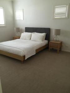 a bedroom with a large bed with two night tables at Beach Front Springs in Rosebud