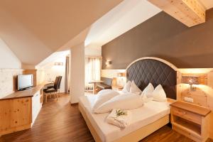 a hotel room with a large bed and a desk at Hotel Am Sonneck in Lagundo