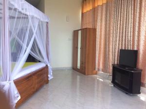 1 dormitorio con 1 cama con cortinas y TV en Auslink Hotel, en Amunumulla