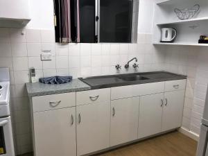 eine Küche mit weißen Schränken und einer Spüle in der Unterkunft Archipelago Apartments Esperance in Esperance + 37 Fotos