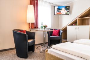 クロルト・アルテンベルクにあるPension Hotel Sartorのベッド、テーブル、椅子が備わるホテルルームです。