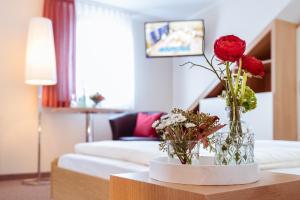 a living room with two vases with flowers on a table at Pension Hotel Sartor in Kurort Altenberg