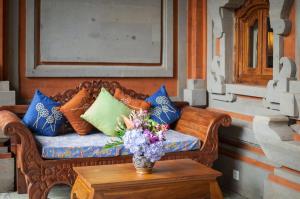 ein Sofa mit Kissen und eine Vase Blumen auf dem Tisch in der Unterkunft Taman Rahasia Tropical Sanctuary and Spa in Ubud