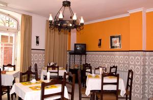 a dining room with white tables and chairs and a chandelier at Hotel Leiriense in Leiria