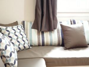 a couch with pillows sitting in front of a window at Villa Victoria Boutique Apartments in Syvota