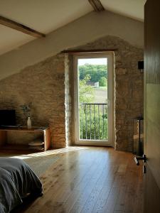 a bedroom with a large window in a stone wall at La Bastide in Lamillarié