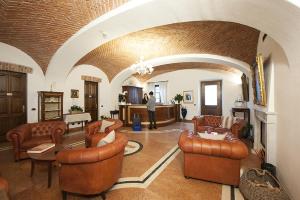 a man standing in a large room with leather furniture at Albergo La Corte Albertina in Bra