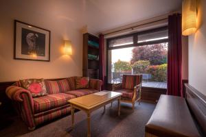 a living room with a couch and a table and a window at Best Western Plus Hostellerie Du Vallon in Trouville-sur-Mer