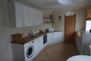 a kitchen with white cabinets and a washer and dryer at Pargi Apartment in Kuressaare