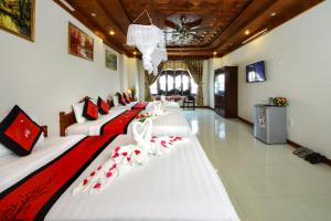 Habitación de hotel con 4 camas con sábanas rojas y blancas en Hoa Mau Don Homestay, en Hoi An