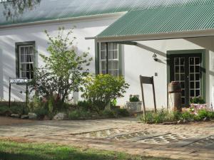 a white house with a green roof and a driveway at Van Rhyn Guest House in Vanrhynsdorp