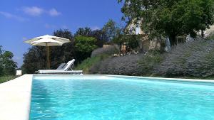 a swimming pool with a chair and an umbrella at La Bastide in Lamillarié