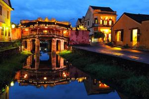 un reflejo de un edificio en un río por la noche en Hoa Mau Don Homestay, en Hoi An