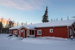 un granero rojo con nieve encima en Soukolo Apartments en Äkäslompolo