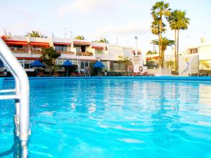 una piscina en un complejo con palmeras y edificios en Apartment Chaparral Complex, en Costa del Silencio