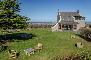 a house with a yard with chairs and a table at Maison de La pointe in Brignogan-Plage