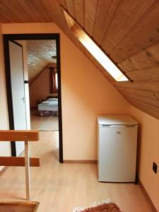 a attic room with a refrigerator and a mirror at Magdaléna Vendégház in Bük