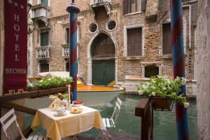 a table in a canal with a boat in the water at Hotel Becher in Venice