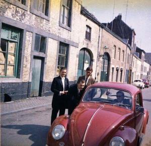 un grupo de personas de pie junto a un coche rojo en Artagnan en Maastricht