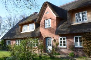a large brick house with a thatched roof at Wohnen Unter Reet in Niebüll