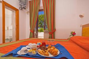 een dienblad met brood en gebak op een bed bij Hotel Bel Tramonto in Ischia