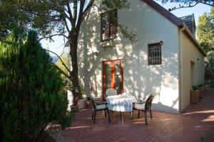 una mesa y sillas frente a una casa en Meadows Mountain View, en Hout Bay