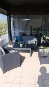 un patio con sillas de mimbre y sofás en un balcón en Apartment en Flensburg