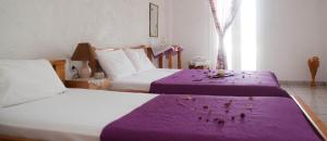 a hotel room with two beds with purple sheets at Villa Xenia in Makry Gialos