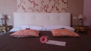 Una cama con dos almohadas y una rosa. en Luxury B&B '700, en Ascoli Piceno