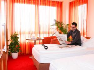 a man sitting on a bed reading a newspaper at Ferienpark Templin direkt neben der Naturtherme in Templin +57 photos